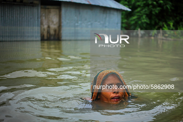 A woman swims in front of her flooded house at Jatrapur area in Kurigram, Bangladesh on Saturday, July 18, 2020. 