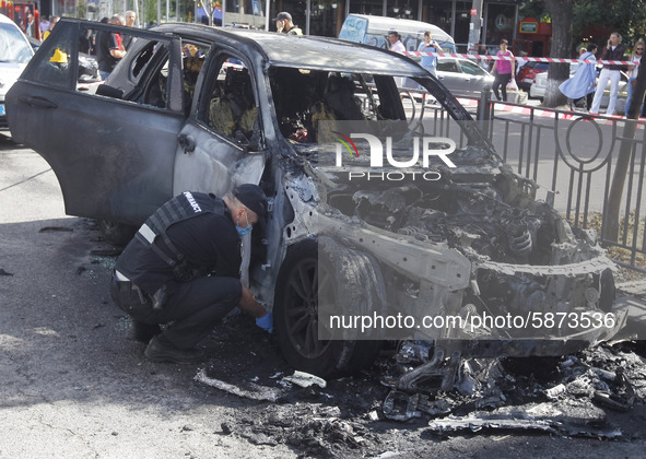 Ukrainian police officers work at the scene near a burned car in the center of Kyiv, Ukraine, on 22 July, 2020. Two parked cars on the roads...