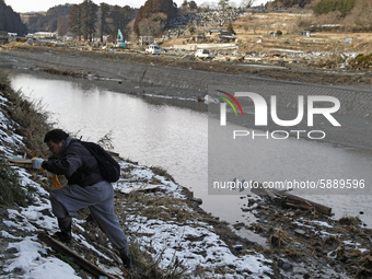 March 17, 2011-Sanriku Minami, Japan-Survivor climbing dike near river at Tsunami hit the destroyed city in Sanriku Minami, north east of To...