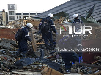 March 18, 2011-Rikuzen Takata, Japan-Rescue Team searching burial person at Debris and Mud covered on Tsunami hit Destroyed city in Rikuzent...