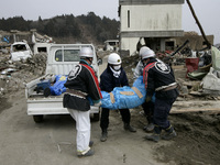 March 20, 2011-Rikuzen Takata, Japan-Volunteer Rescue Team Carry exhumed body on debris and mud covered at Tsunami hit Destroyed city in Rik...