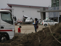 March 22, 2011-Sendai, Japan-Mom and son wait for taxi on debris and mud covered at Tsunami hit Destroyed Airport in Sendai on March 22, 201...