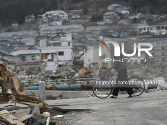 March 23, 2011-Ofunato, Japan-Old Bikeman looking to debris and mud covered at Tsunami hit Destroyed Industrial Area in Ofunato on March 23,...