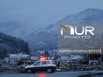 March 24, 2011-Sanriku, Japan-Police vehicle patrol around snow falling on debris and mud covered at Tsunami hit Destroyed empty village in...