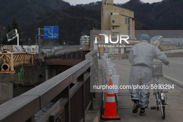 March 25, 2011-Kamaishi, Japan-Old bike man cross broken bridge on debris and mud covered at Tsunami hit Destroyed mine town in Kamaishi on...