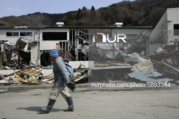 March 25, 2011-Kamaishi, Japan-Native survivor pass to debris and mud covered at Tsunami hit Destroyed mine town in Kamaishi on March 25, 20...