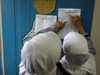 A Palestinian student looks up her name and classroom on a list at a United Nations-run school as a new school year begins as Palestinians e...