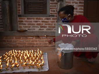 A Nepalese devotee along with the face mask offers butter lamps outside the temple, due to the covid-19 pandemic, less number of Nepalese de...