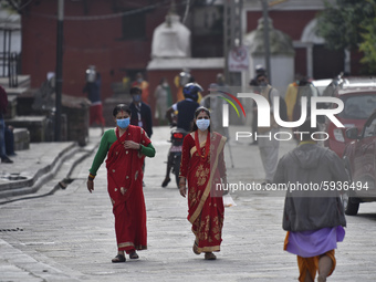 Nepalese devotees along with face mask arrive to offer ritual prayer outside the Pashupatinath Temple gate during Teej festival celebrations...
