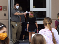 Principal Nathan Hay checks the temperatures of students as they return to school on the first day of in-person classes in Orange County at...