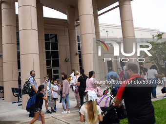 Parents walk their children to school on the first day of in-person classes in Orange County at Baldwin Park Elementary School on August 21,...