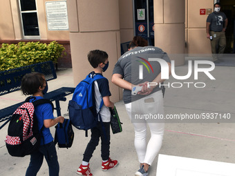 A  school employee escorts children as they return to school on the first day of in-person classes in Orange County at Baldwin Park Elementa...