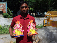 An artist poses with the idols of the elephant-headed Hindu deity Lord Ganesh ahead of beginning the Ganesh Chaturthi festival starting from...