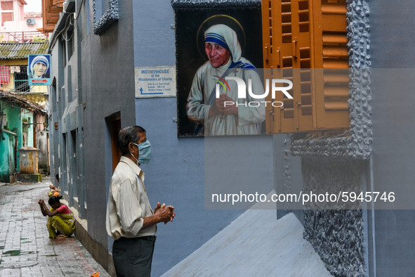 A gentleman prays in front of a picture of Saint Teresa , outside Missionaries of Charity in Kolkata.A lady offer her prayers from outside t...