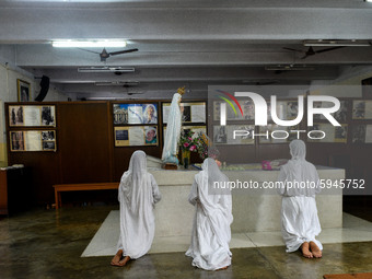 Catholic Nuns of order of Missionaries of Charity offers prayers at the tomb of Saint Teresa.A lady pray in front of a picture of Saint Tere...
