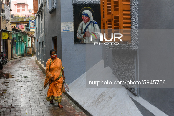 A lady wearing mask walks past a picture of Saint Teresa outside Missionaries of Charity Kolkata.A nun offers her prayer to the tomb of Sain...