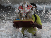 A Volunteer immerses an idol of the Hindu god Ganesha, into the Arabian Sea during the Ganesh Chaturthi festival in Mumbai, India on August...