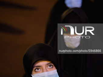 An Iranian veiled woman wearing a protective face mask looks on while attending a Moharram religious ceremony in the Imam Hussein square in...