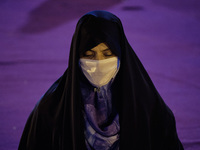 An Iranian veiled woman wearing a protective face mask attends a Moharram religious ceremony in the Imam Hussein square in southern Tehran o...