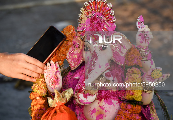 A devotee whispers a wish over phone in the ear of an idol of Hindu deity Ganesha, as part of a ritual on the occasion of Ganesha Chaturthi,...
