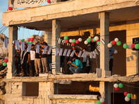 Syrians demonstrate in an anti-Assad demonstration near the rubble of a building that was hit in a previous bombing and decorated with the f...
