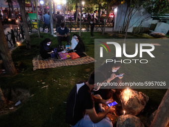 An Iranian couple use their smartphones as they sit next to candles on a street-side while attending a ceremony to commemorate Ashura, in no...