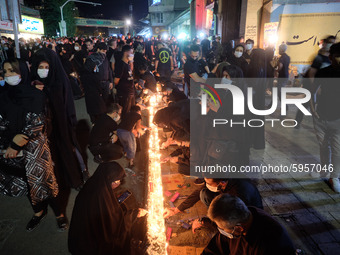 Iranians wearing protective face masks light candles while attending a ceremony to commemorate Ashura, in northern Tehran on August 30, 2020...