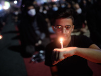 An Iranian man holds a candle on his hand while attending a ceremony to commemorate Ashura, in northern Tehran on August 30, 2020, amid the...