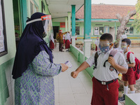 A teacher check body temperature of a student at Candirejo Elementary School, Semarang Regency, Central Java, Indonesia, on September 1, 202...