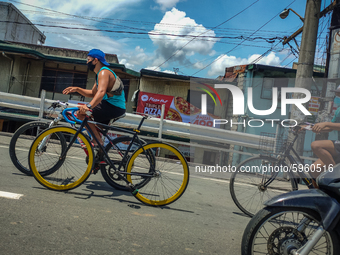 Biker in Pasig City, Philippines supporting a sport's bike while riding in another bicycle in Rosario Bridge, Pasig, on September 1, 2020 (