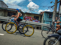 Biker in Pasig City, Philippines supporting a sport's bike while riding in another bicycle in Rosario Bridge, Pasig, on September 1, 2020 (