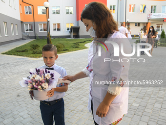 Physician measures temperature First grader during the ceremony on the occasion of the beginning of the new school year against the backgrou...