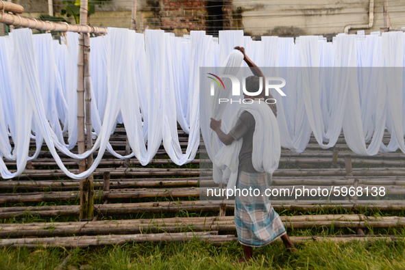 A worker dry fabric under the sun after dyeing them in a factory in Narayanganj, Bangladesh on September 03, 2020. 
