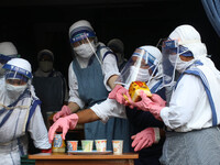 Nun's from the Catholic Order of the Missionaries of Charity wearing a facemask and shield distributes food packets and tea to underprivileg...
