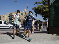 Two children waves and run with facemasks during the first day of school on September 10, 2020 in Granada, Spain.  (