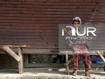 A muslim girl sits on a bench outside a closed shop in Khudgoo Mungluu area of sopore,  district baramulla Jammu and Kashmir,  India on 13 S...