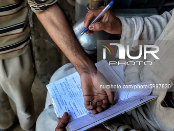 A man writes a mobile phone number on the wrist of another in Khudgoo Mungluu area of sopore,  district baramulla Jammu and Kashmir,  India...