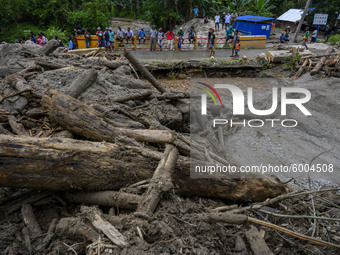 Residents are in front of piles of wood that have piled up roads and houses due to flash floods in Rogo Village, Dolo Selatan District, Sigi...
