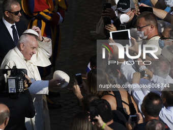 Pope Francis exchanges a skull cap which was donated by faithful as he arrives in the St. Damaso courtyard on the occasion of his weekly gen...