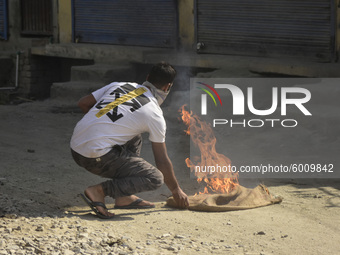 A Kashmiri protester lights a fire to reduce the effect of teargas during protests after the encounter ended in Batamaloo area of Srinagar,...