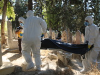 Volunteers from the Syrian Civil Defense, also known as the White Helmets, wear protective clothing and bury a death from the Coronavirus in...