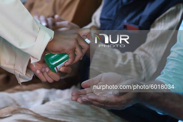 A man puts hand sanitizer on a participant during Annual Conference amid COVID-19 (coronavirus) Pandemic Held at Jamia Islamia Quran in Sopo...
