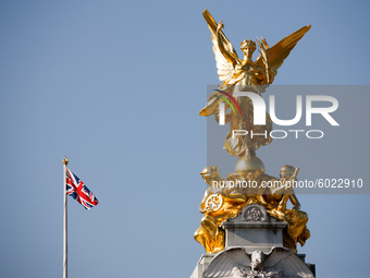 The gilded bronze 'Winged Victory' sculpture atop the Victoria Memorial glints in sunlight in front of a Union Jack flying from the roof of...