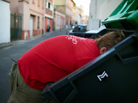 Tarin dives in a trash container. Tarin, a young man, searches for food in trash containers next to supermarkets. When needed he rides his b...