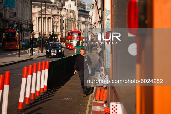 A woman walks along Piccadilly within temporary pavement barriers installed to aid social distancing in London, England, on September 22, 20...