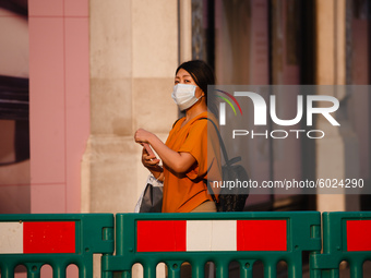 A woman wearing a face mask pauses behind temporary pavement barriers, installed to aid social distancing, on Regent Street in London, Engla...