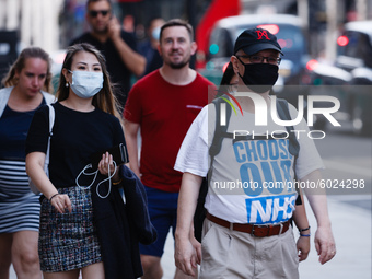 A man wearing a face mask and t-shirt bearing a message of support for the National Health Service (NHS) walks along Regent Street in London...