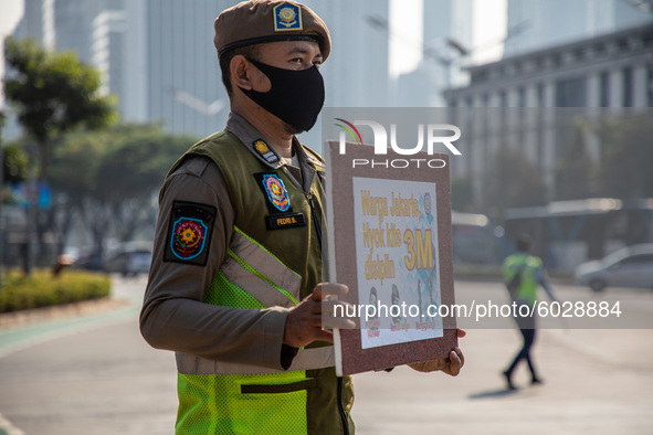 City Guard with sign of Keep Distance, Washing hands, and use mask campaign at Sudirman Street Jakarta on 24 September 2020. Jakarta's retur...