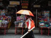 A woman with umbrella to avoid heat at Pasar Baru, Central Jakarta passing by an empty store without visitior on 24 September 2020. Jakarta'...