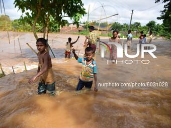 Childrens wades through a flooded area, following heavy rainfall at Juripar village in Nagaon  in the northeastern state of Assam, India, on...